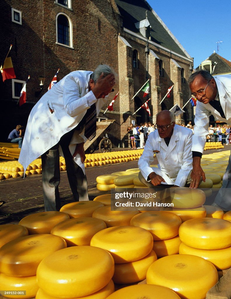 Holland,Alkmaar,men in white overalls looking at cheese