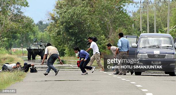 Indonesian journalists take position during a gun fire exchange between Indonesian military and the separatist rebel Free Aceh Movement in Aceh...