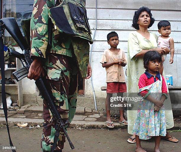 An Acehnese woman and her children watch a government soldier checks residents identity after a gun fire exchange between Indonesian military and the...