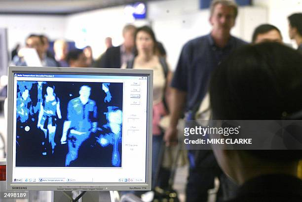 Passengers have their temperature checked inside the arrival hall at Hong Kong International Airport 09 September 2003. The announcement of a fresh...