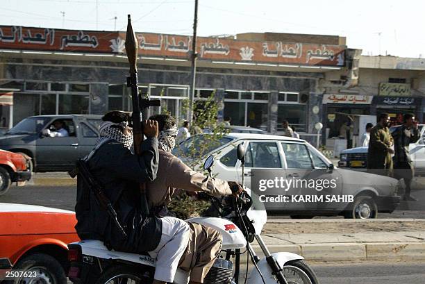 Masked Iraqi youth on a motorcycle carries an RPG during the funeral for Iraqi policemen -- killed accidentally in a firefight by US troops -- 13...