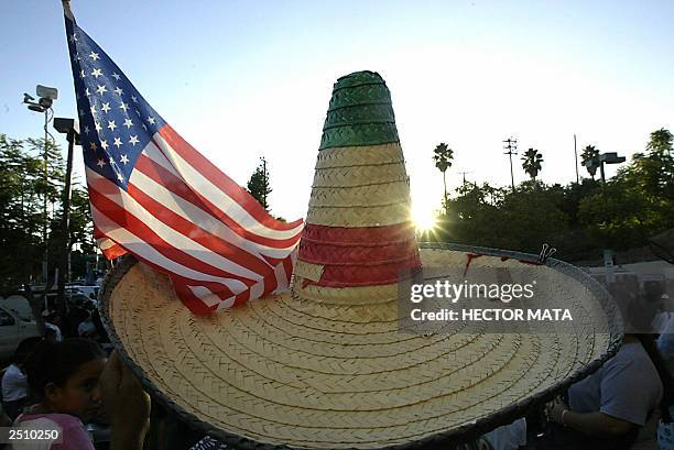 Man wearing a Mexican holds a US flag as Governor of California Gray Davis signs a bill giving the rights to illegal inmigrants to apply for a...