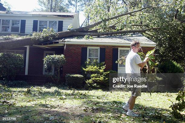 Tom Evertt picks up branches on his lawn after a tree fell on his home when Hurricane Isabel passed through September 19, 2003 in Poquoson, Virginia....