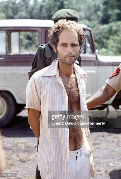 People's Temple follower Larry Layton stands with police following his arrest November 18, 1978 in the shooting of two people on a remote Guyana...