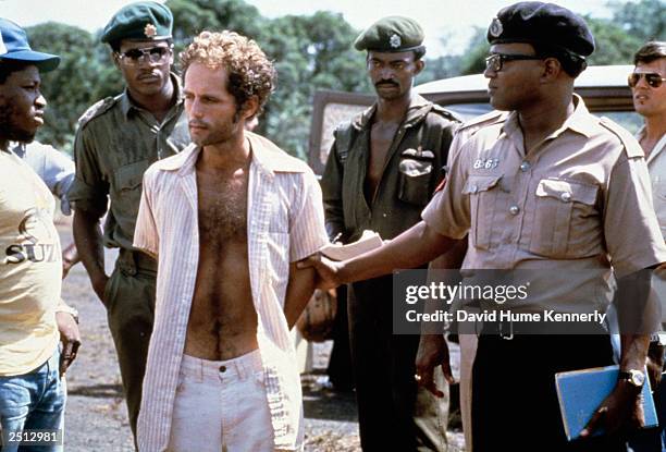 People's Temple follower Larry Layton stands with police following his arrest November 18, 1978 in the shooting of two people on a remote Guyana...