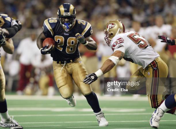 Marshall Faulk of the St. Louis Rams avoids the tackle of Jeff Ulbrich of the San Francisco 49ers on September 14, 2003 at the Edward Jones Dome in...