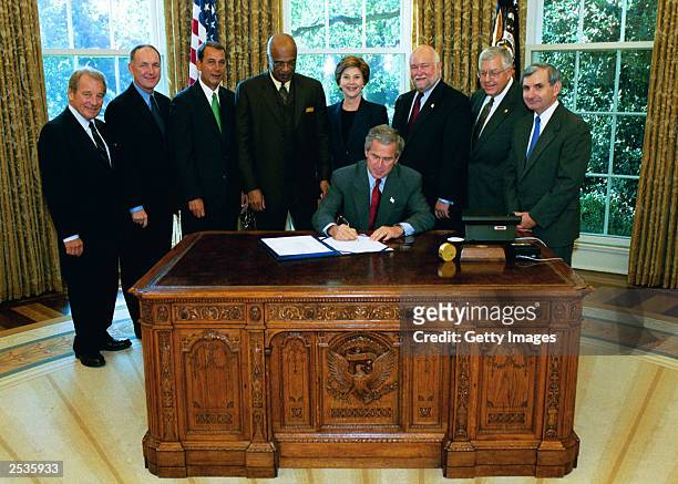 In this White House handout photo, President George W. Bush signs into law, H.R. 13, the Museum and Library Services Act of 2003, in the Oval Office...