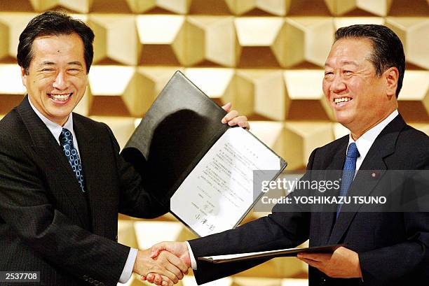 Japan's largest opposition Democratic Party of Japan leader Naoto Kan and the smaller opposition Liberal Party leader Ichiro Ozawa exchange documents...