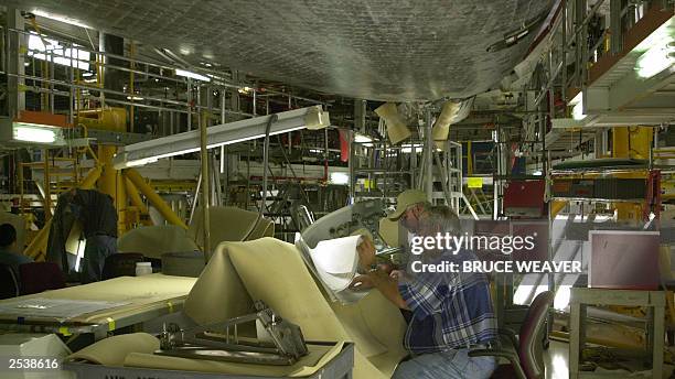 Technicians check the specifications on one of space shuttle Atlantis' wing leading edge reinforced carbon carbon section, 26 September 2003, under...