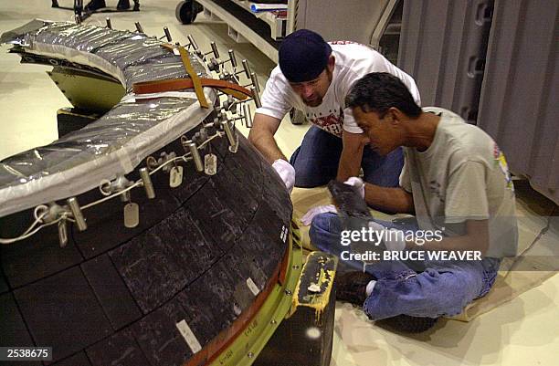 Technicians install heat resistant tiles on one of space shuttle Atlantis' main engine domes heat shields 26 September at the Kennedy Space Center,...