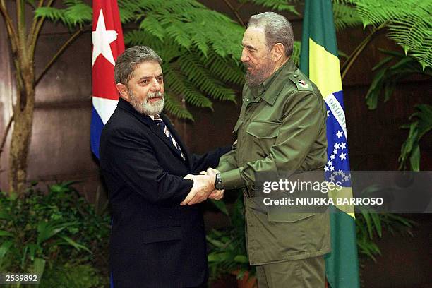 Brazilian President Luiz Inacio Lula da Silva and Cuban President Fidel Castro shake hands in front of their respective national flags posing for the...