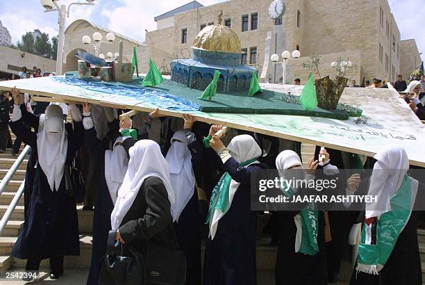 Palestinian women carry a model of the Al-Aqsa mosque, Islam's third most holy site, during the demonstrations for marking the beginning of second...