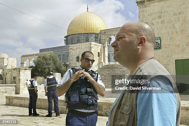 An Israeli policeman keeps on eye on an Israeli visitor outside the Dome of the Rock Islamic shrine on the Temple Mount, known to Muslims as el-Harem...