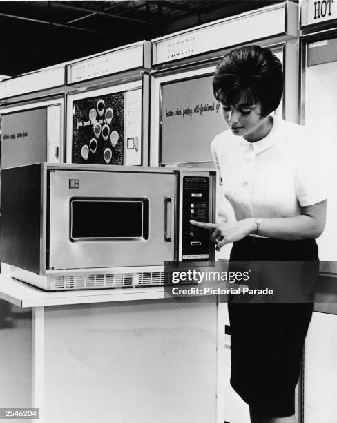 Woman demonstrates a Litton Series 500 microwave oven on a display stand, circa 1966.