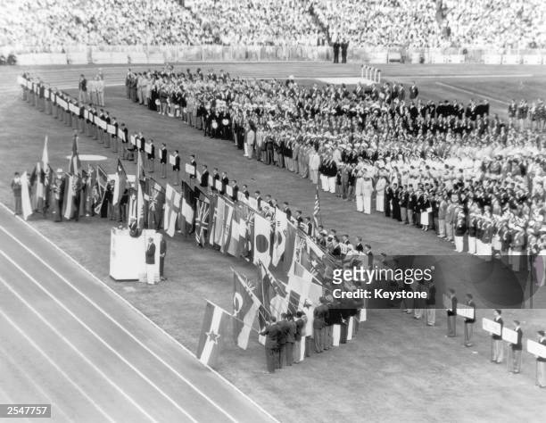 Australian athlete John Landy stands at the podium and takes the Olympic oath while athletes from competing nations hold their national flags during...