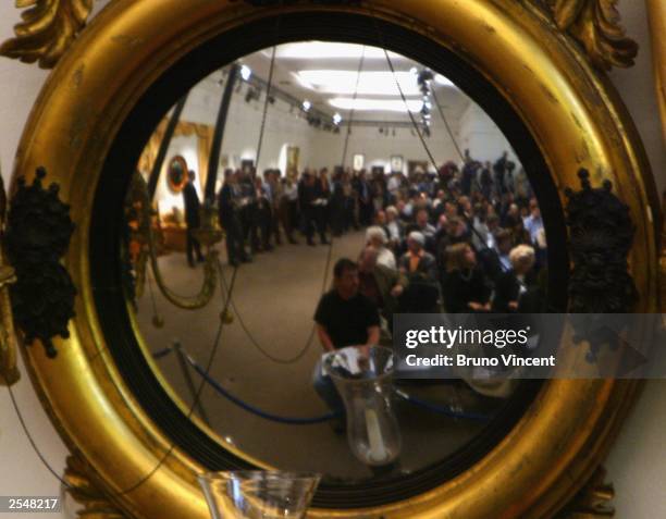 Reflection of the auction room is seen in a Gilt-Gesso convex mirror expected to make ?8,000 to ?12,000 from the Holland Park home of Sir Elton John...