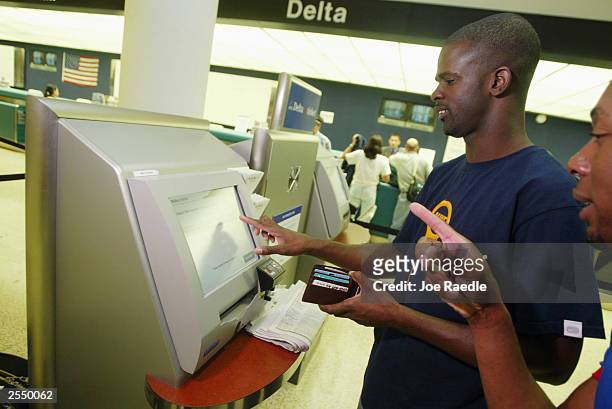 Fenton Bratford and Steve Roberts use a computer to purchase their e-tickets at the Delta airlines counter in the Miami International Airport...