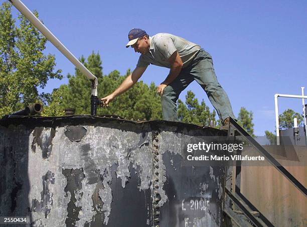 Independent oil producer, Steve McLaurin, checks the amount of oil in one of his tanks that is being sold for the current price of 25 dollars a...