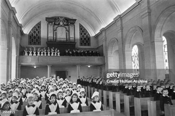 Girls and boys sit on separate pews in the chapel of a London foundling hospital, 3rd May 1941. Picture Post - 444 - Foundling Hospital