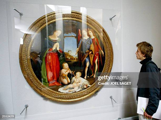 A person looks at the painting called "Adoration de l'Enfant, Saint-Jean et les anges musiciens" of Italian painter Piero di Cosimo as he visits the...