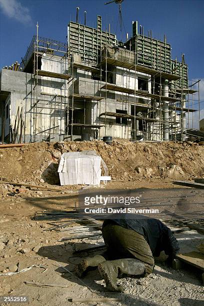 Palestinian laborer bows during his Muslim afternoon prayers at a new housing construction site October 1, 2003 of the West Bank Jewish settlement of...