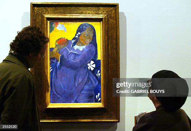 Visitors look at "La Femme a la fleur", a painting dated 1891 by French Paul Gauguin as they discover the "Gauguin-Tahiti" exhibition 01 October 2003...