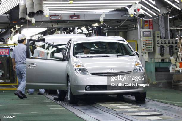 In this handout image released by Toyota Motor Corporation, Toyota employees check the new-generation Prius hybrid for final inspection at Toyota's...