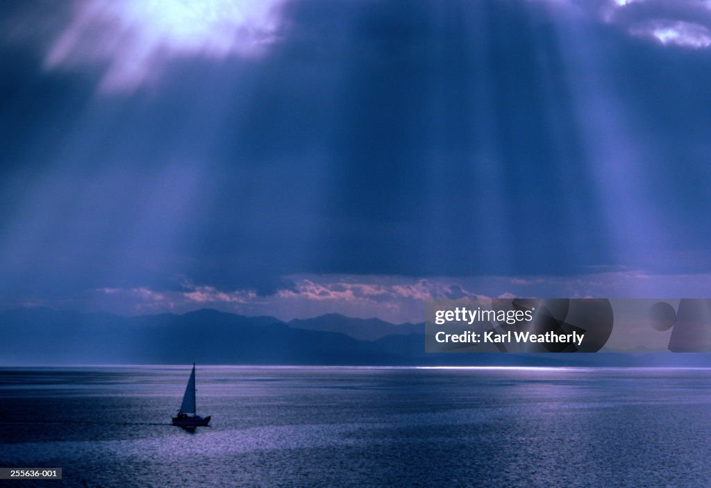 Boat on calm sea,sun breaking through cloud above