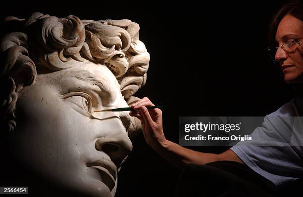 Restorer Cinzia Parnigoni cleans Michelangelo's masterpiece "David" during restoration work at the Galleria dell'Accademia October 6, 2003 in...