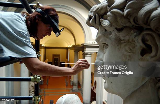 Restorer Cinzia Parnigoni cleans Michelangelo's masterpiece "David" during restoration work at the Galleria dell'Accademia October 6, 2003 in...