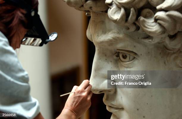 Restorer Cinzia Parnigoni cleans Michelangelo's masterpiece "David" during restoration work at the Galleria dell'Accademia October 6, 2003 in...