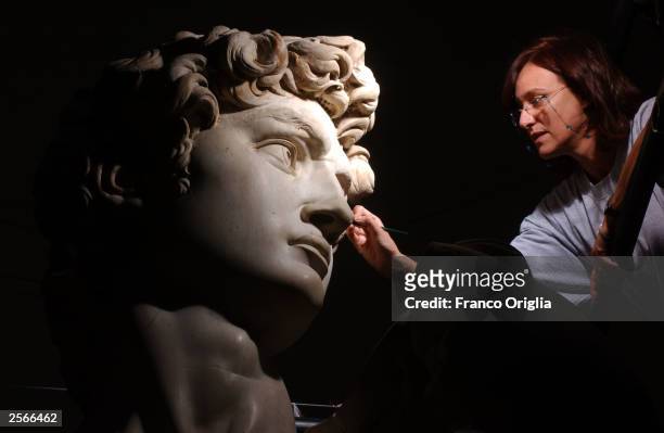 Restorer Cinzia Parnigoni cleans Michelangelo's masterpiece "David" during restoration work at the Galleria dell'Accademia October 6, 2003 in...