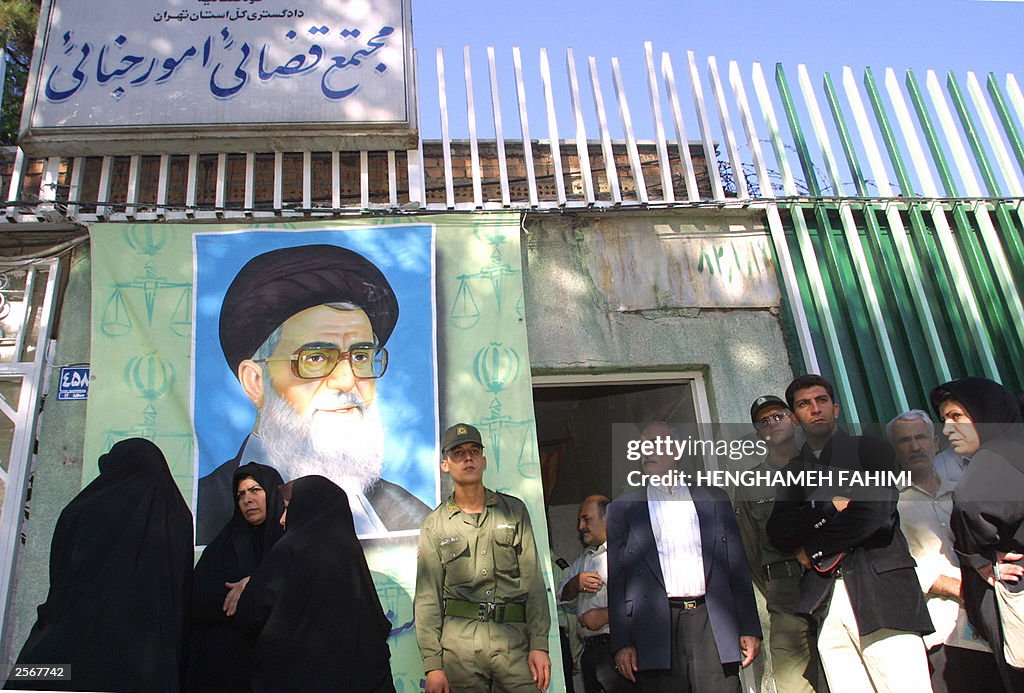 People look on as Iranian soldiers stand