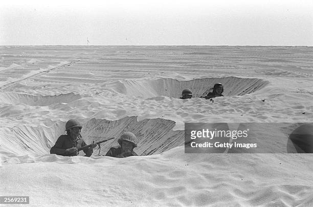 Israeli soldiers take cover in their foxholes during fighting against the Egyptians October 14, 1973 in the Sinai Desert during the Yom Kippur War....