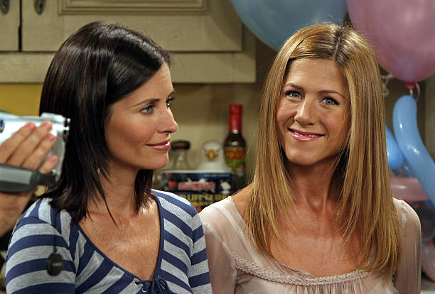 Courteney Cox Arquette and Jennifer Aniston smile on the set of the hit NBC series "Friends" during one of their last shows on the Warner Bros lot...