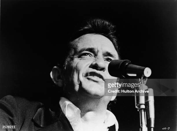 Headshot of American country singer Johnny Cash singing on stage in a still from the film, 'Johnny Cash - The Man, His World, His Music,' directed by...