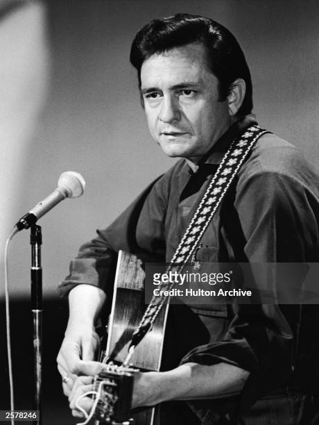 American country singer and songwriter Johnny Cash plays acoustic guitar in a still from his television variety series, 'The Johnny Cash Show,' circa...