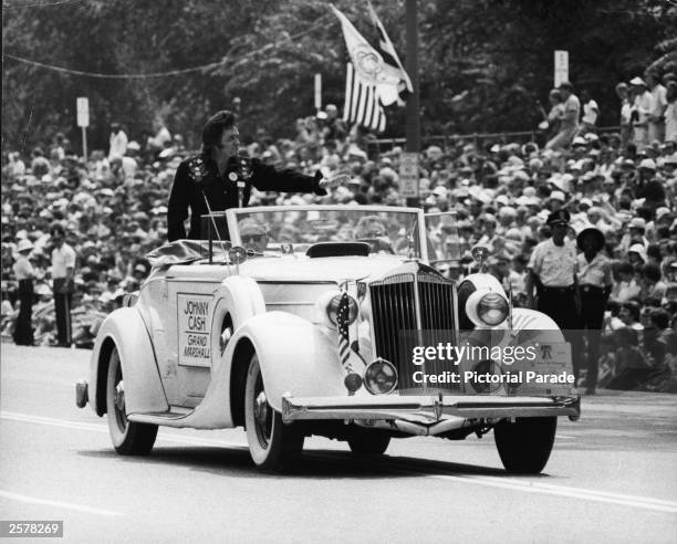 American country singer Johnny Cash waves as he stands in the back of a vintage 1936 Packard convertible. Cash served as Grand Marshal of the Grand...