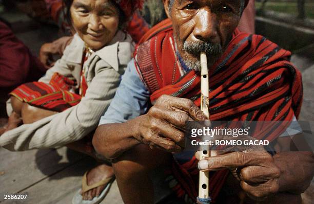 Ifugao montain tribesman Tomas Guinyang plays bamboo flute beside tribeswoman Bugan Agudong in Banaue town park located in northern Philippine...
