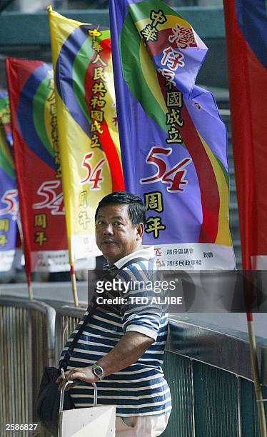 Man stands next to banners promoting the 54th anniversary of founding of the People''s Republic of China in Hong Kong, 30 September 2003, one day...