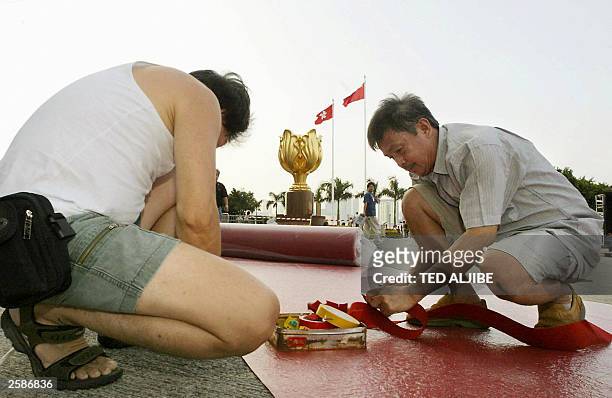 Workers install a red carpet outside the Hong Kong Exhibition and Convention Centre grounds, 30 September 2003, where a flag raising ceremony will be...