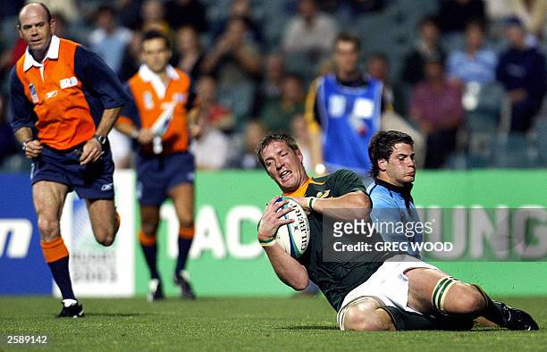 Lock Bakkies Botha from South Africa slides in to score a try after avoiding Fulback Joaqui Pastore of Uruguay, with referee Paddy O''Brien , during...