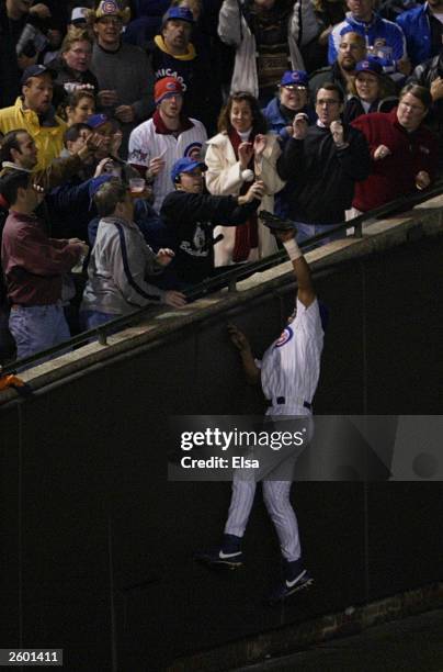 Fans interfere with outfielder Moises Alou of the Chicago Cubs on a ball hit by Luis Castillo of the Florida Marlins scoring two runs in the eighth...