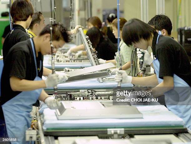 Employees of Samsung Electronics set up large LCD TV on a production line at Samsung Electronics factory in Suwon 07 August 2003. South Korea's...