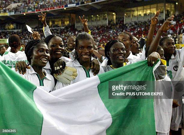 Members of the Nigerian women's soccer team hold up their national flag, late 16 October, 2003 after winning the All Africa Games final over South...
