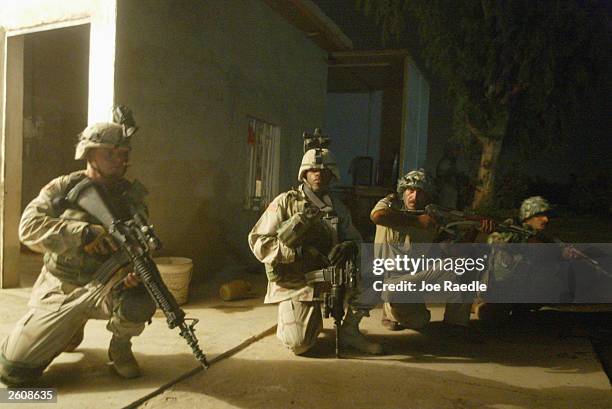 Army soldiers from the 299th Engineering Battalion of the Fourth Infantry Division and Iraqi civil defense corpse personnel keep an eye out as they...