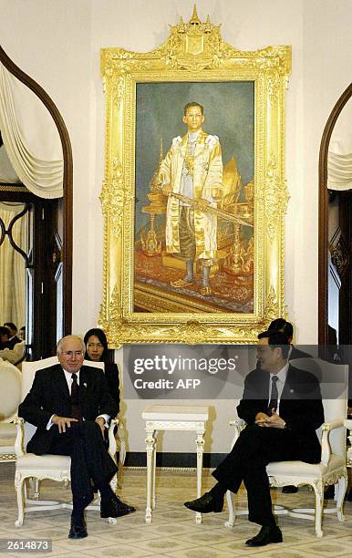 Thai Prime Minister Thaksin Shinawatra meets his Australian counterpart John Howard in front of a huge portrait of Thai King Bhumibol during their...