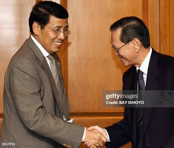 Singapore's ambassador to Indonesia, Edward Lee , shakes hands with Indonesia's Foreign Minister Hassan Wirayuda during the signing of an agreement...