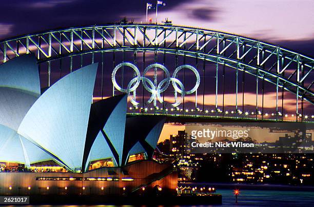 Sunset over the Olympic Rings on the Sydney Harbour Bridge and the Opera House as the Olympic Games loom on Sydney Harbour, Sydney, Australia....
