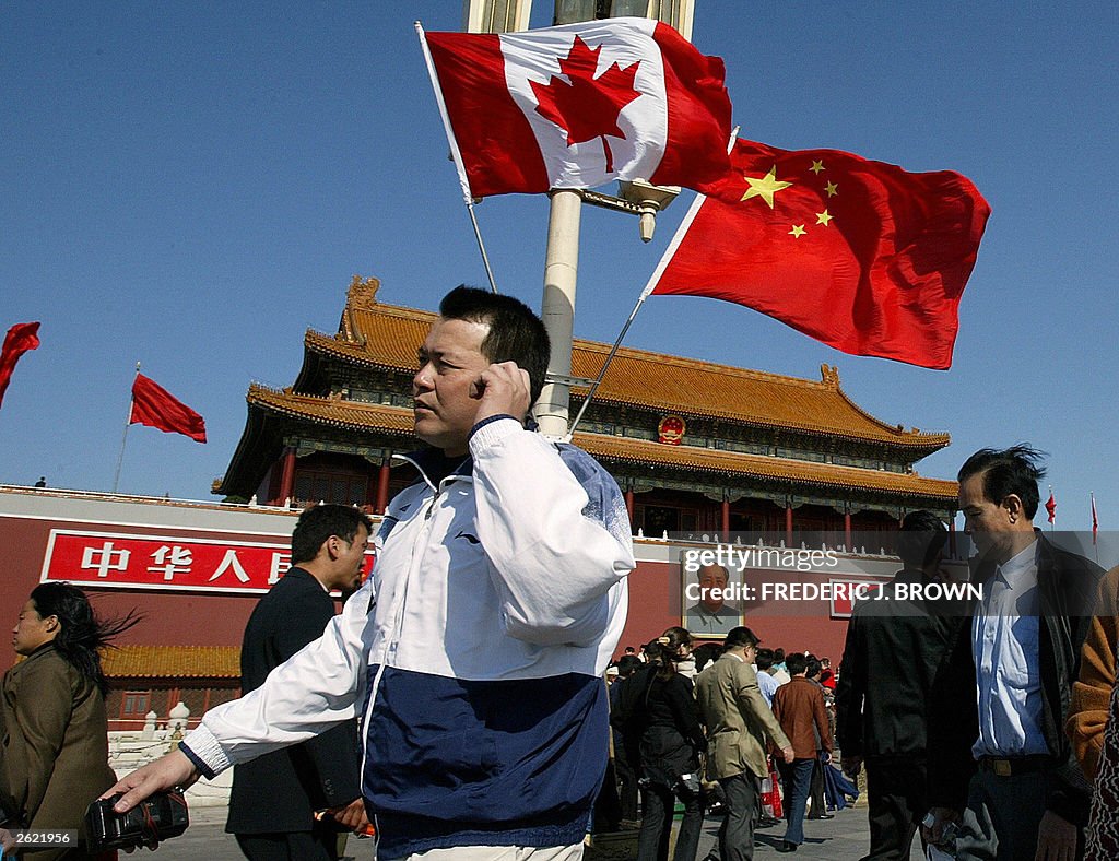 A man walks past flags of Canada and Chi